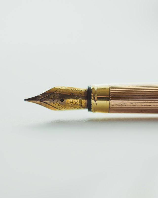A brass fountain pen on a white surface