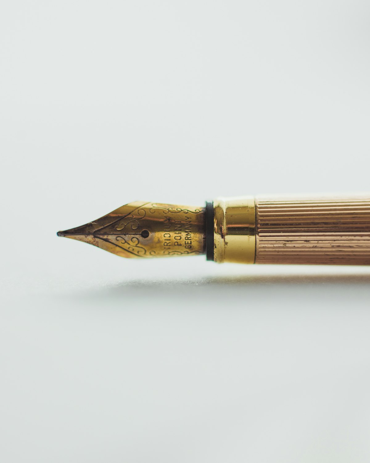 A brass fountain pen on a white surface