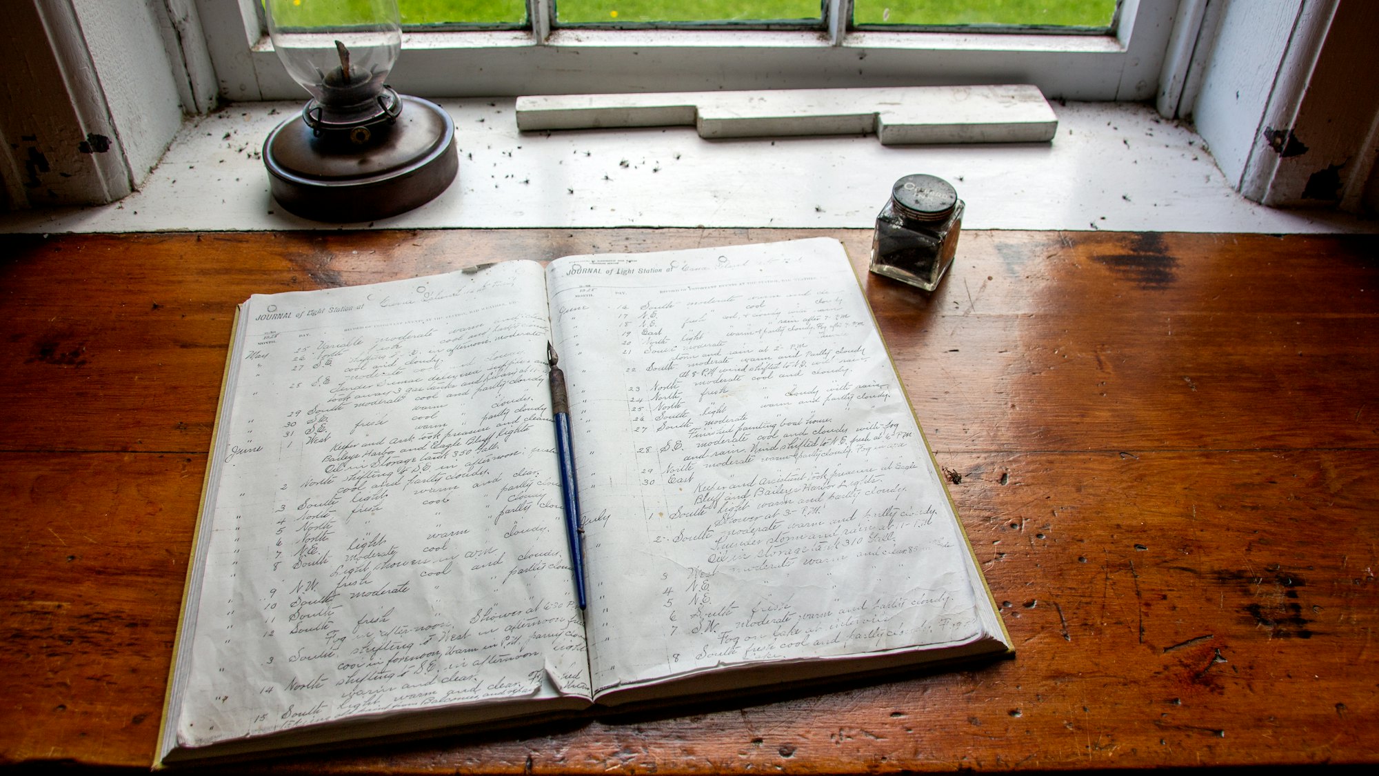An open notebook on a wooden desk by a window