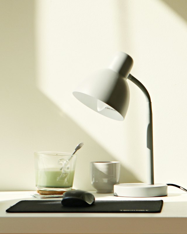 A desk lamp on a sunlit white desk