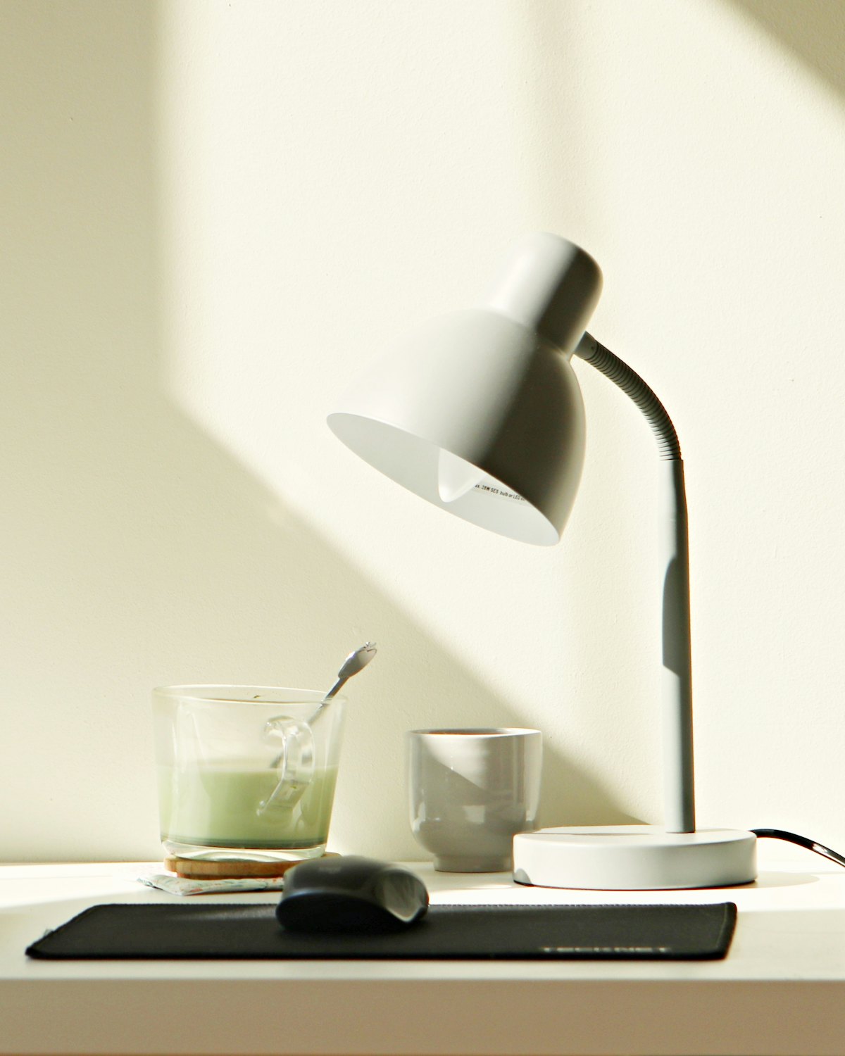 A desk lamp on a sunlit white desk